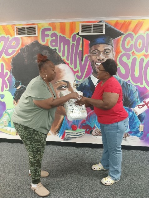LISC AmeriCorps member Cassandra Ford (left) distributes diapers and wipes to an Eastside resident during her Poundin’ for C.A.K.E event. 