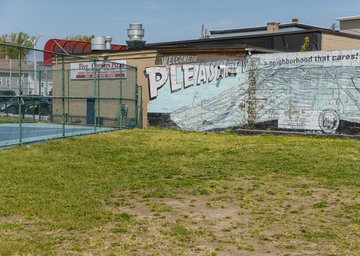 a mural reading "Pleasant View" and a chain link fence surrounding a basketball court